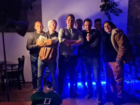 Konrad and other comedians on stage under blue light