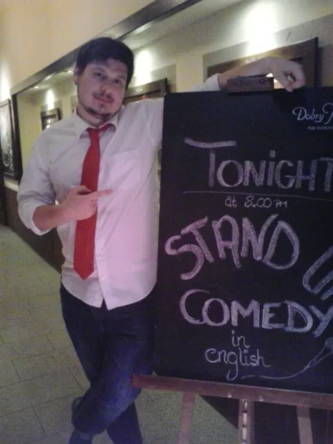 Konrad beside a chalkboard reading Tonight Stand Up Comedy, Dobry Kumpel Pub, Kraków, 2017