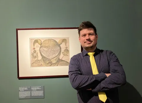 Konrad standing beside a framed artwork