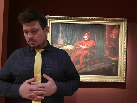 Konrad in front of a painting of a court jester
